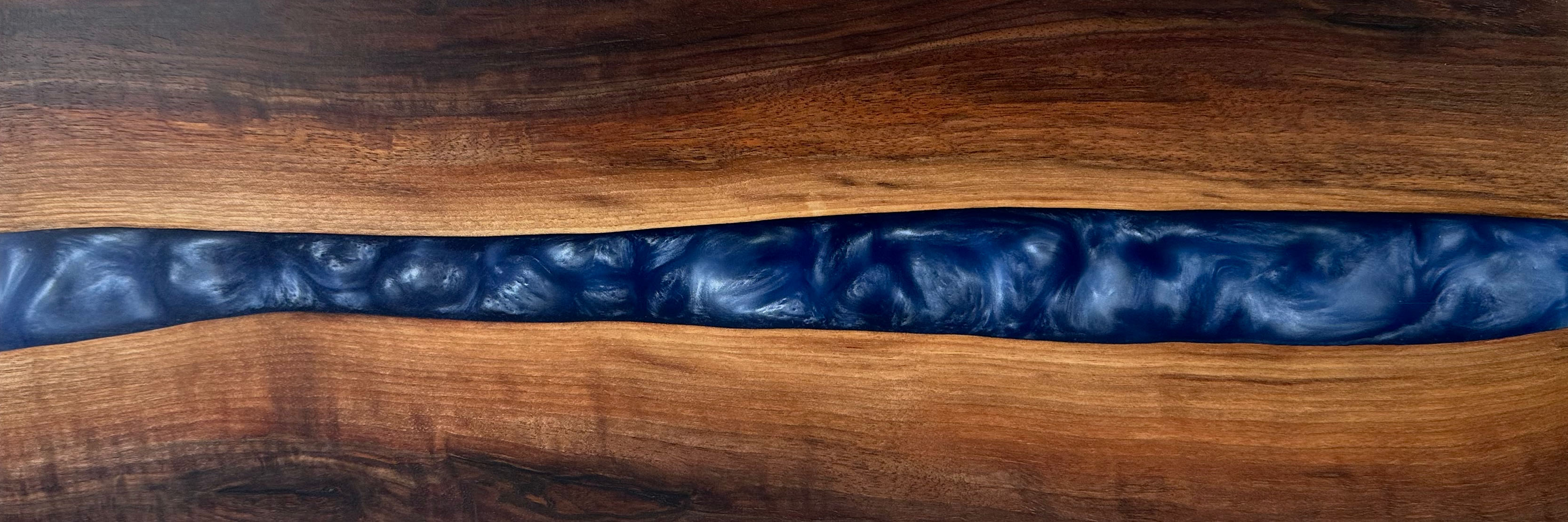 live edge walnut with a blue swirling epoxy resin river through the center